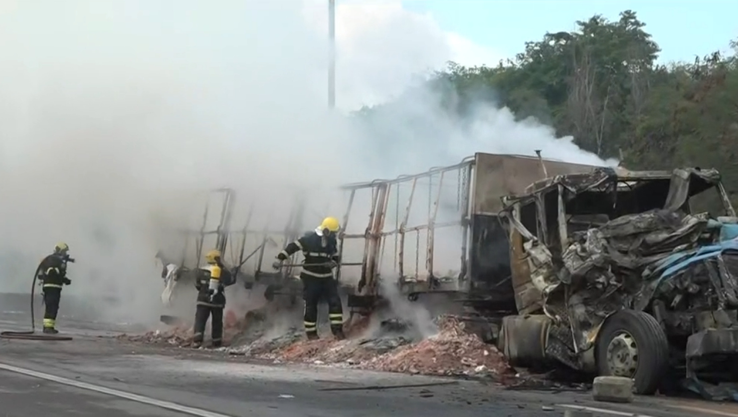Imagem da carreta em chamas na Rodovia do Contorno, com fumaça densa saindo do local e veículos envolvidos no acidente.
