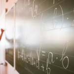 Professor escreve equações matemáticas no quadro em sala de aula